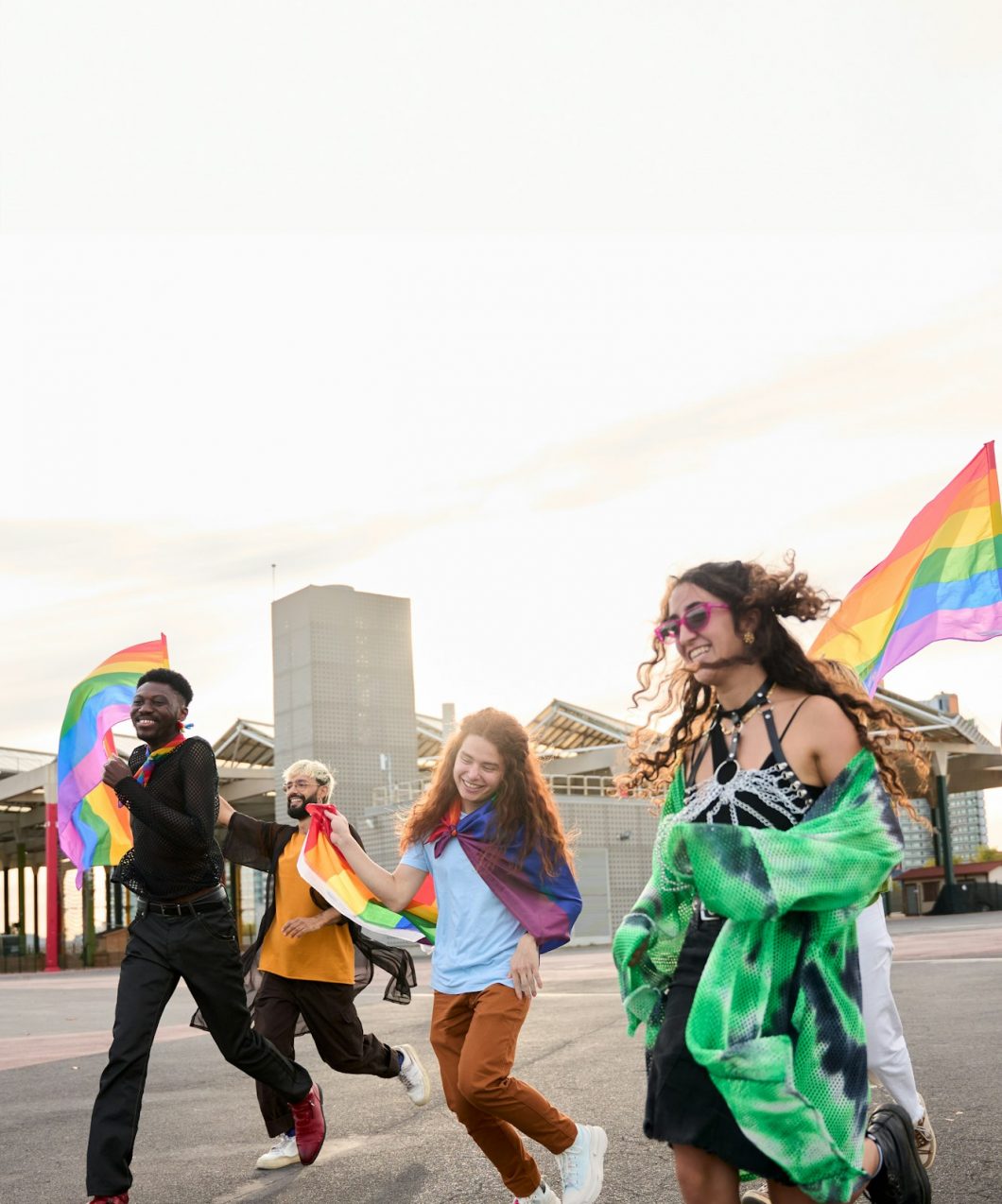 A happy group dances down the street holding rainbow flags